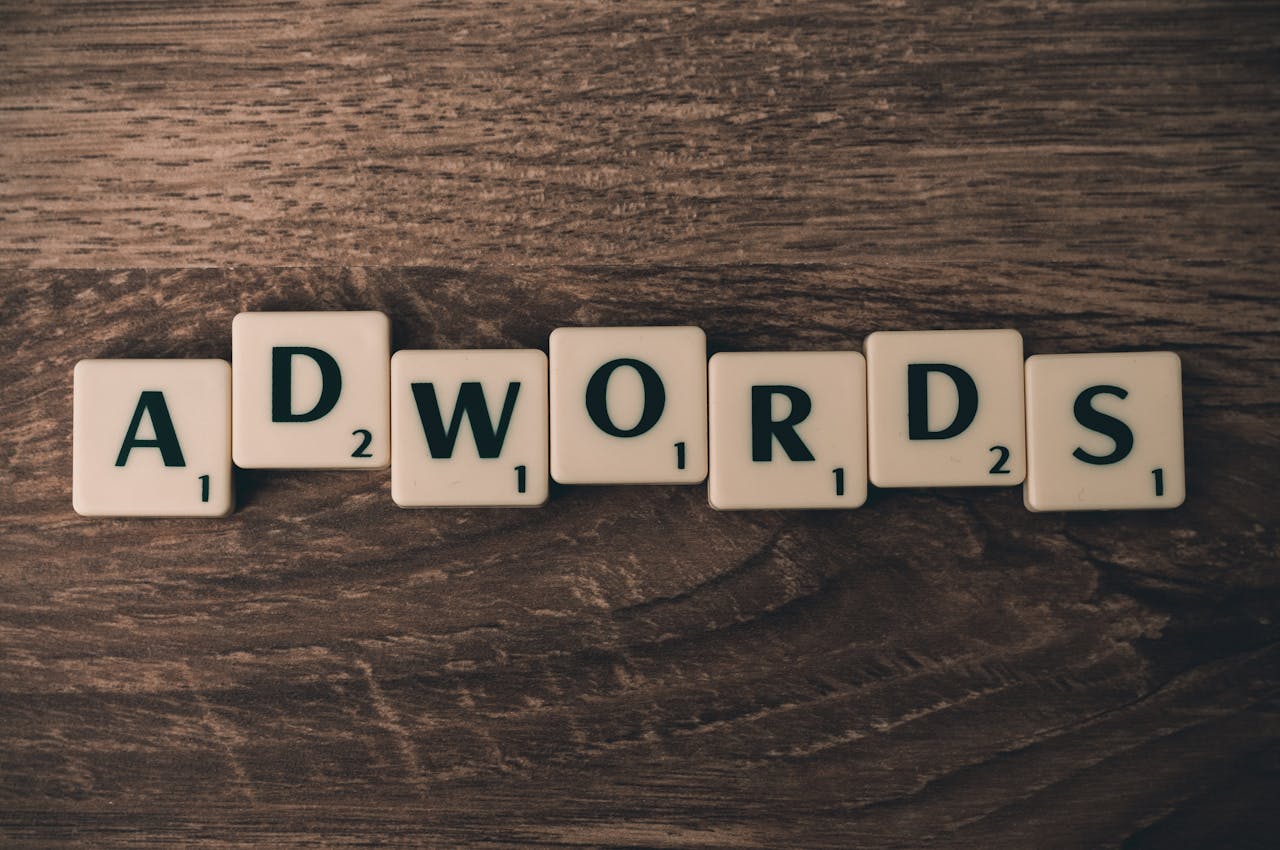 Scrabble tiles spelling AdWords on a wooden surface, symbolizing digital marketing concepts.